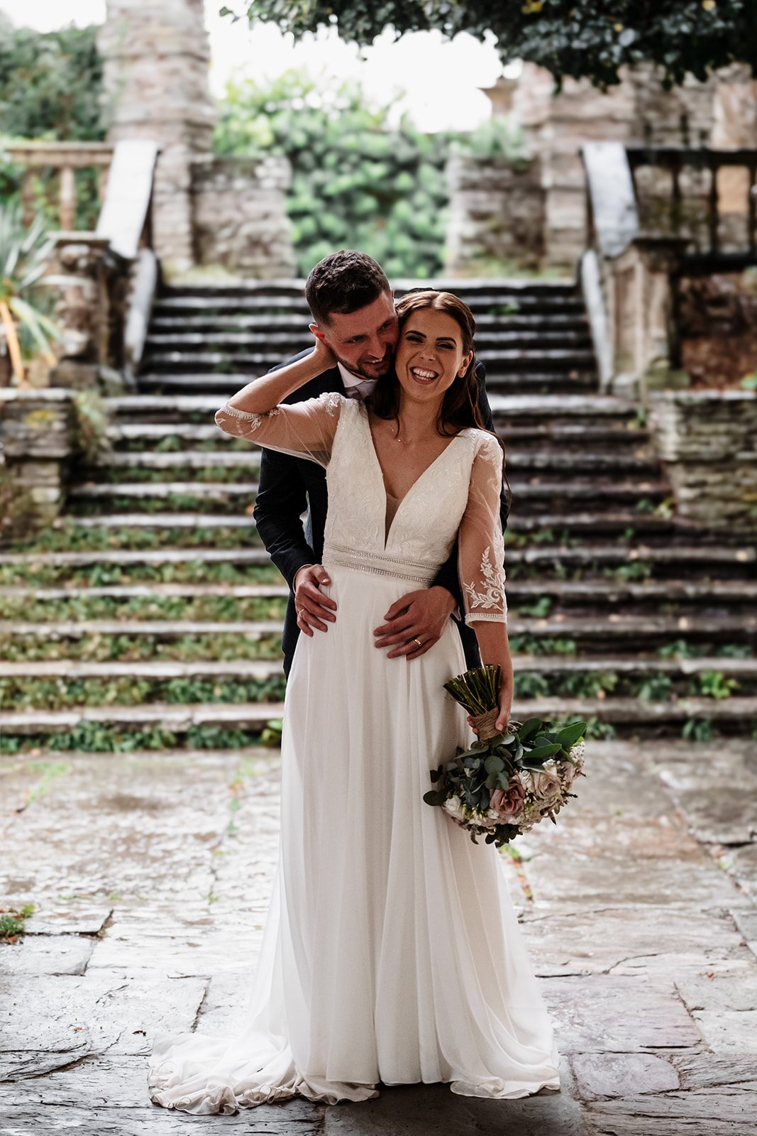 Alice and Josh smiling together beside the garden steps at Hestercombe