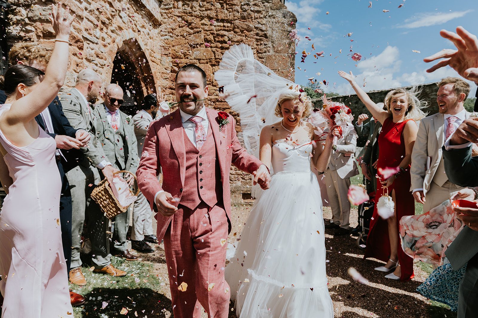 Barney and Ellie laughing beneath confetti outside the church