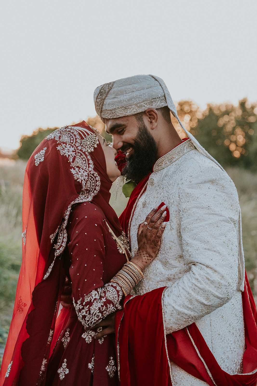 The Choudhurys smiling together in red and ivory wedding attire