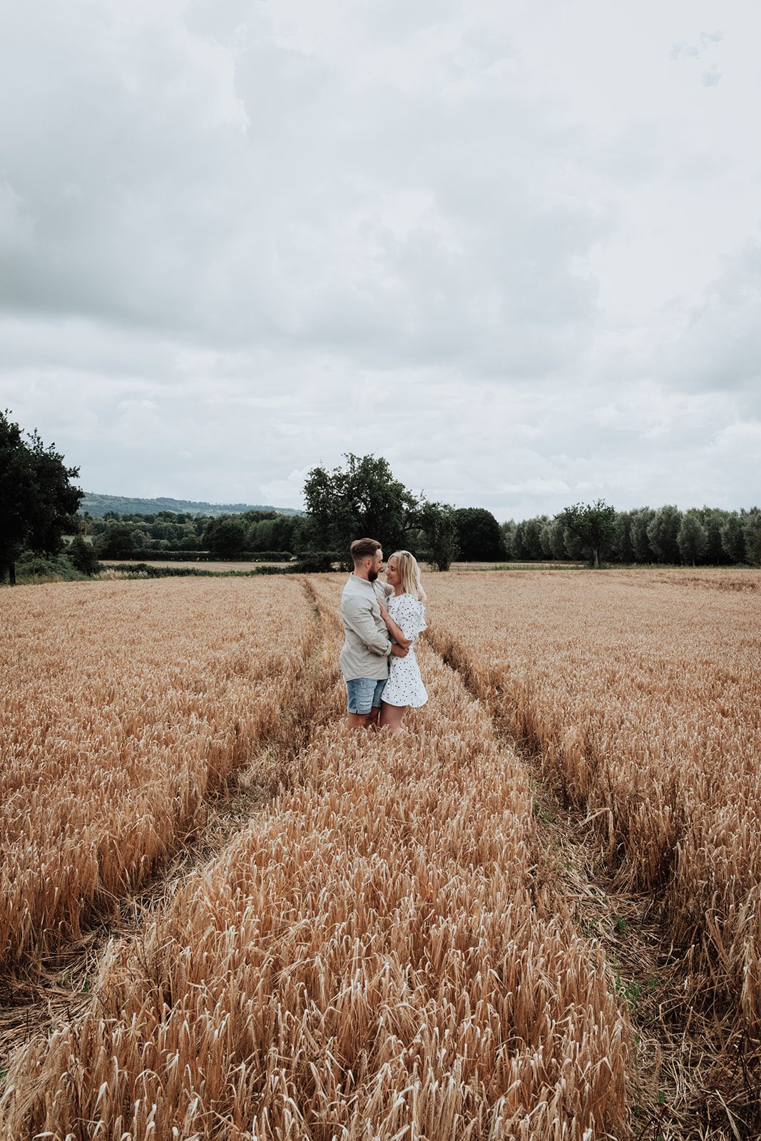 Holly and Thomas embracing in a golden wheat field