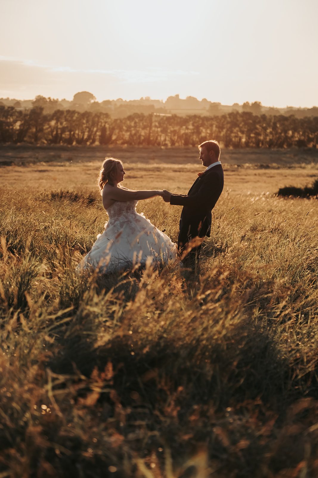 Harriet and Richard holding hands in a field at golden hour