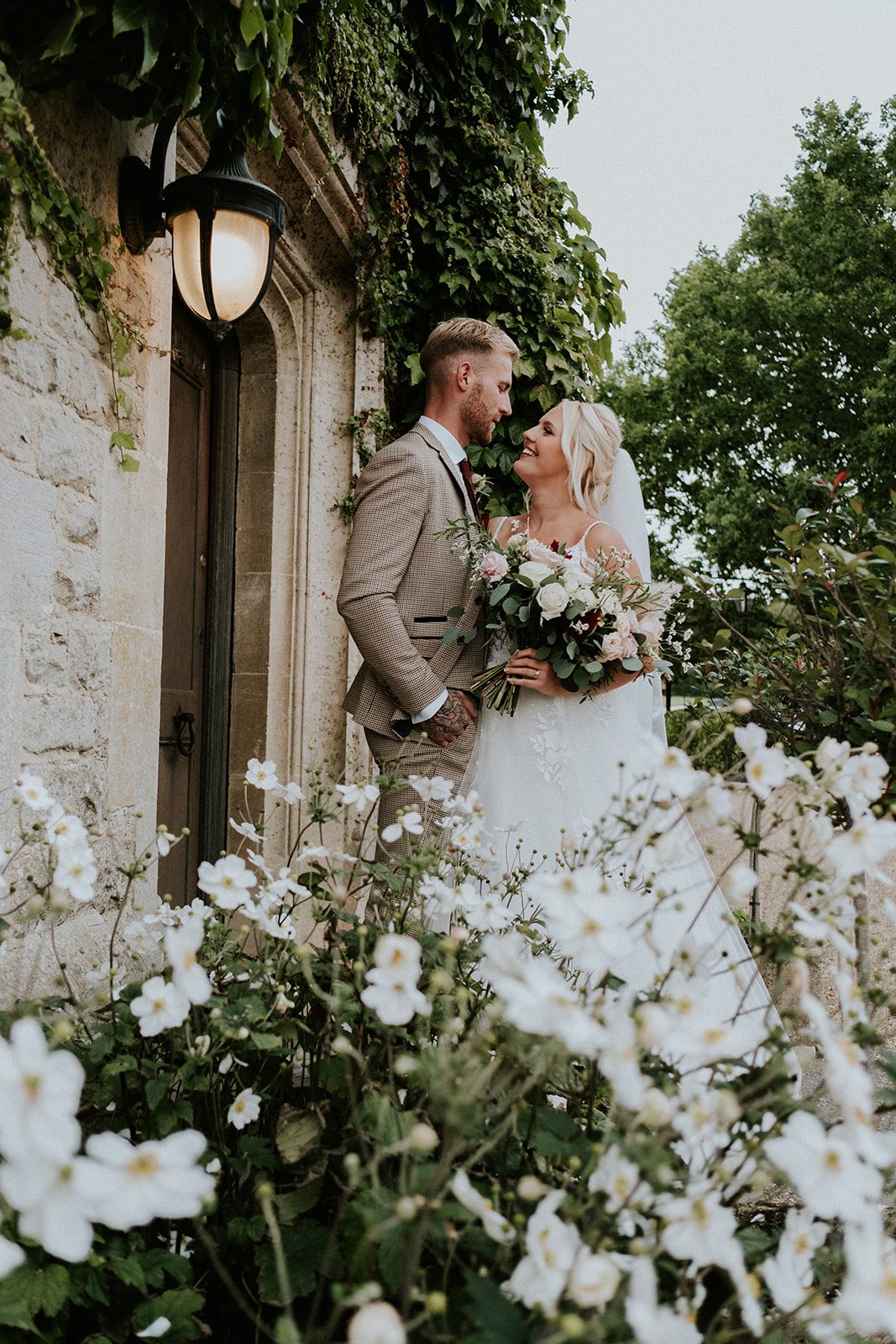 Izzie and Todd smiling together beside an ivy-covered doorway