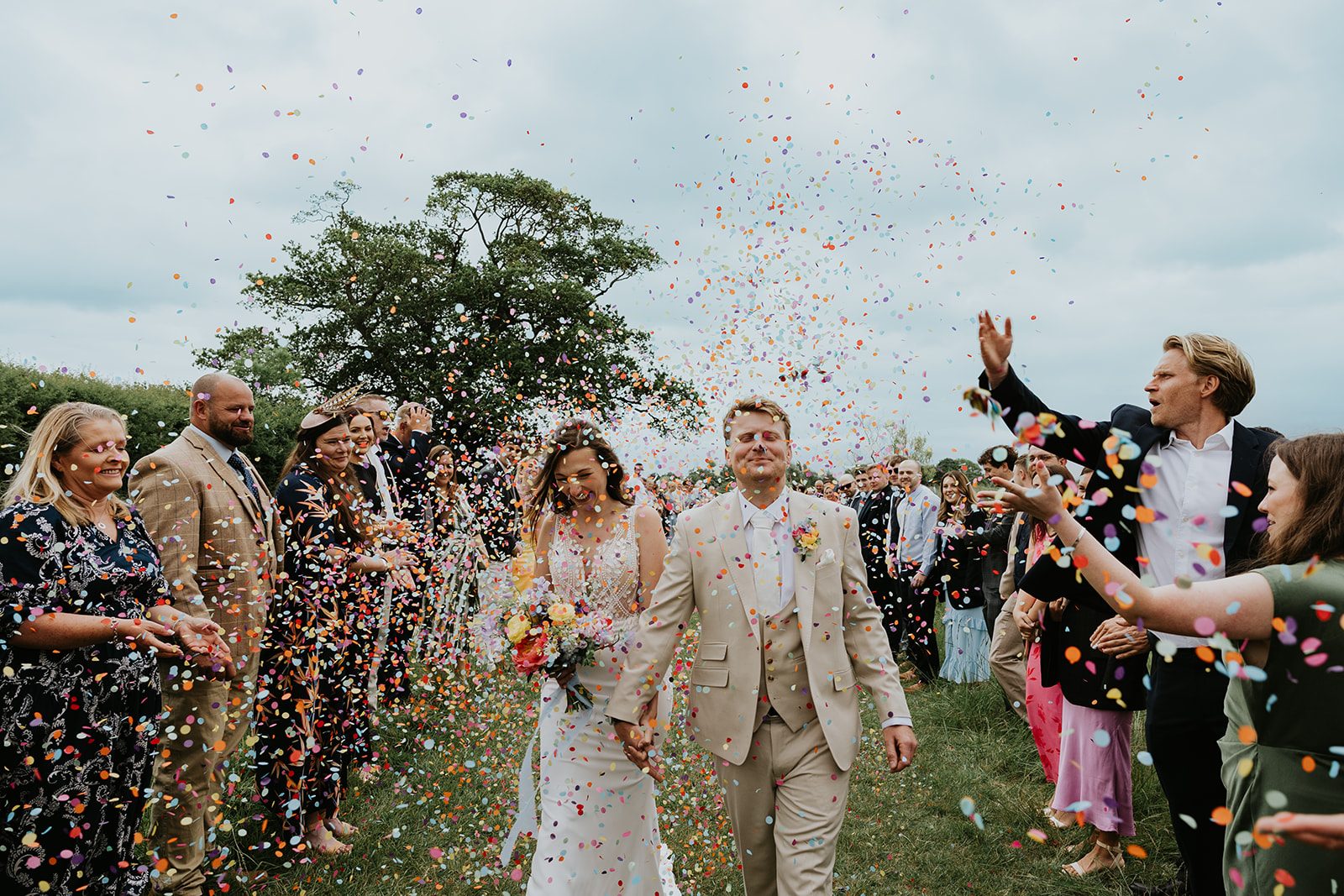 Jade and Paul laughing beneath a shower of colourful confetti