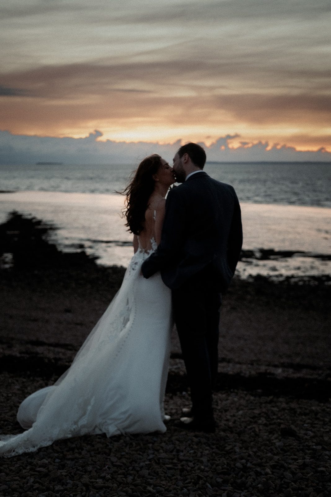 Lou and Mike kissing beside the sea at sunset in Clevedon