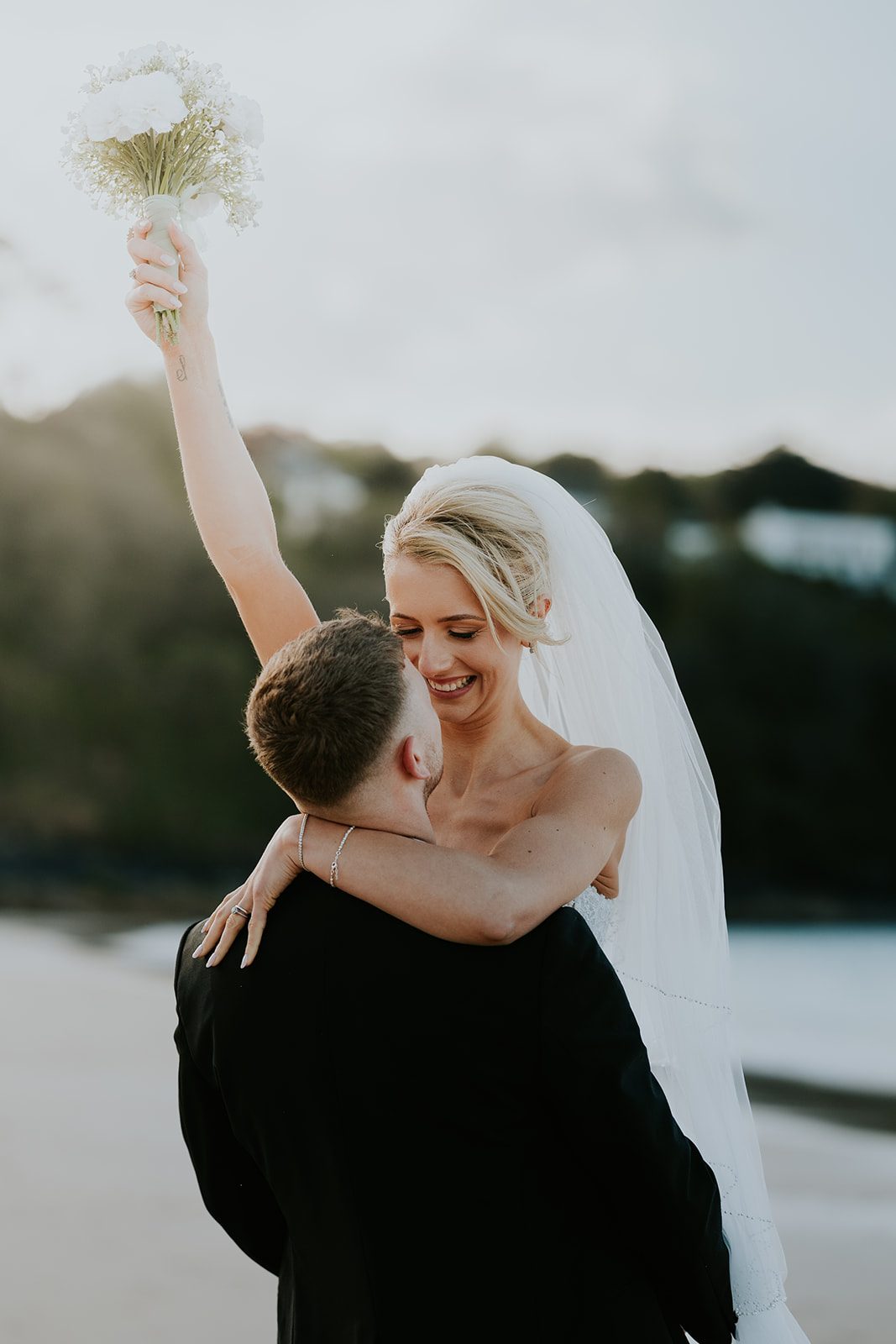 Pete lifting Maisie with her bouquet raised in the air
