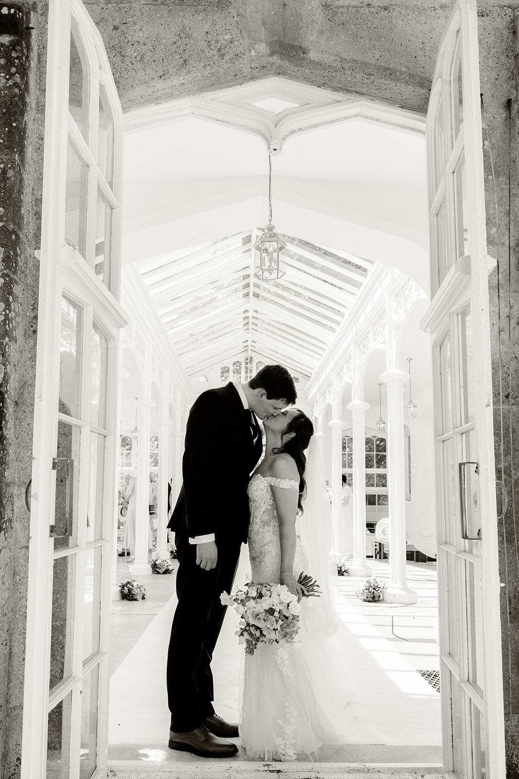 Nataya and Ali kissing in an orangery doorway, in black and white