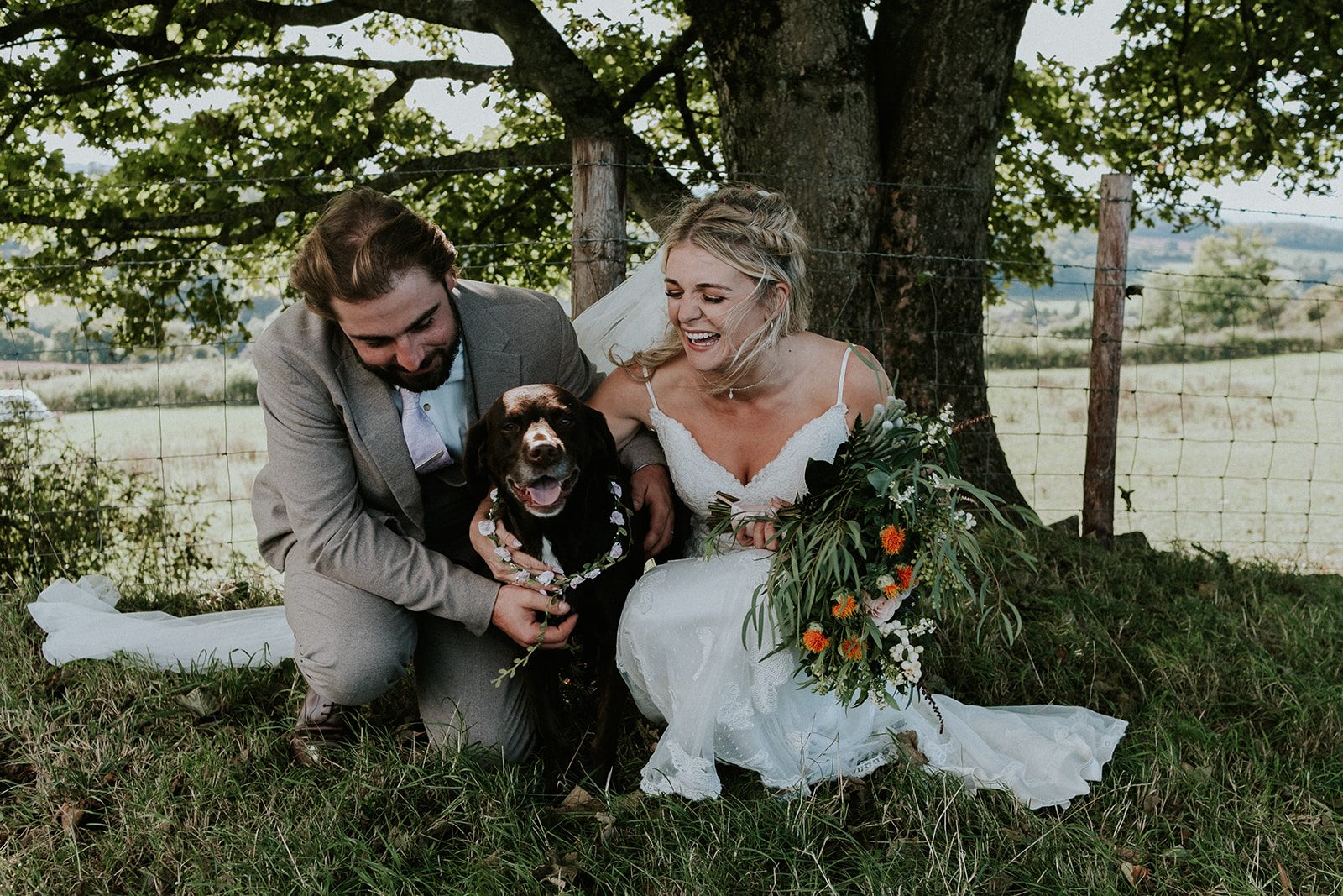 Sally and Harry laughing with their dog beneath a tree