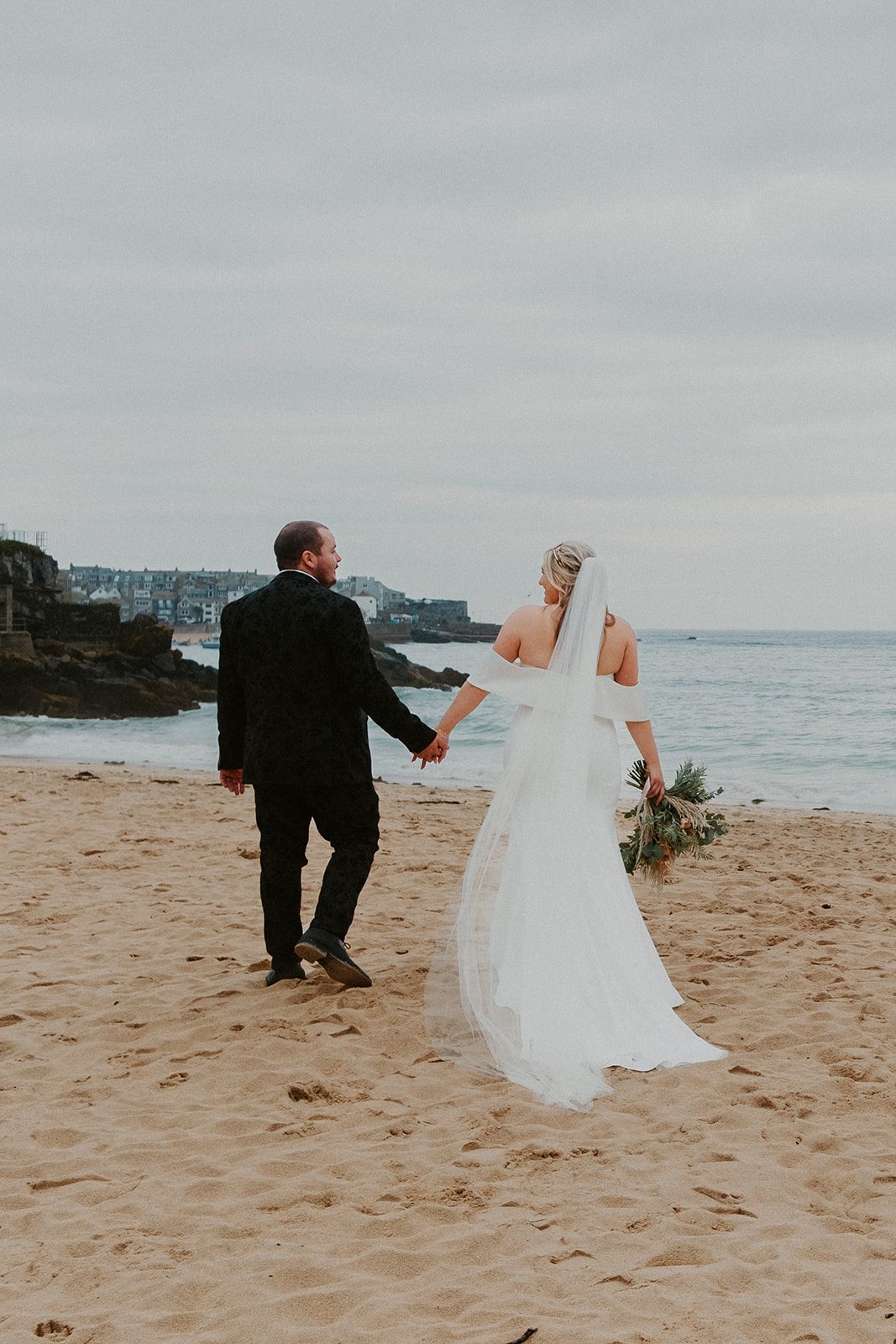 Wallis and Christopher walking hand in hand on the beach at St Ives