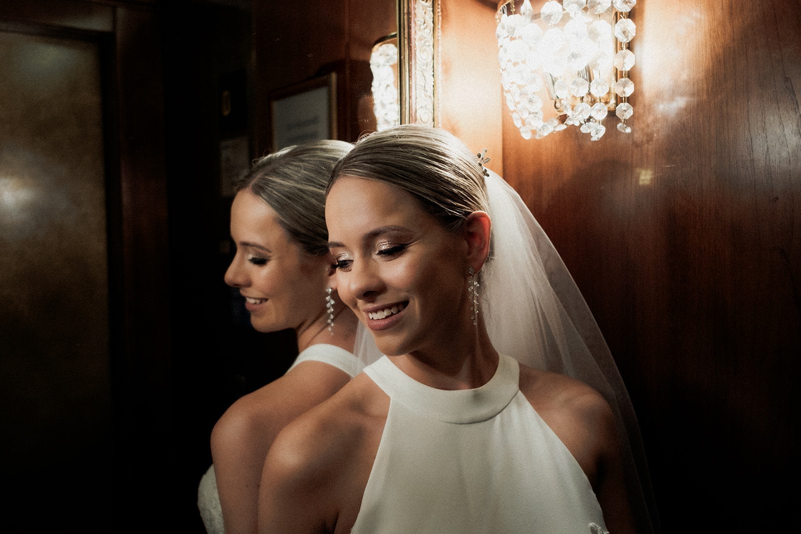 Zoe smiling beside her reflection in warm light at her Lake Bled wedding
